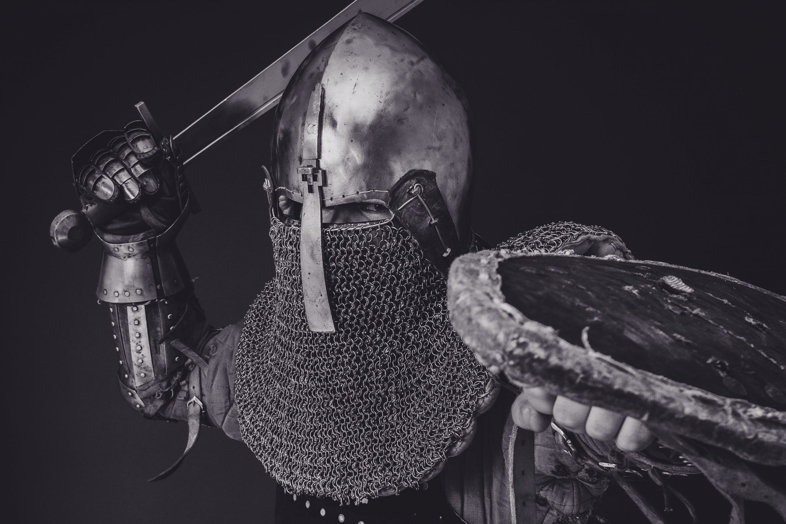 Man in armor stands poised with sword and shield