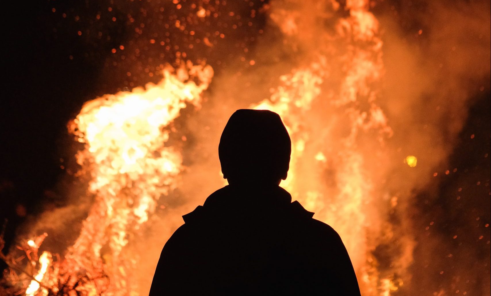 Silhouette of a man facing a fire