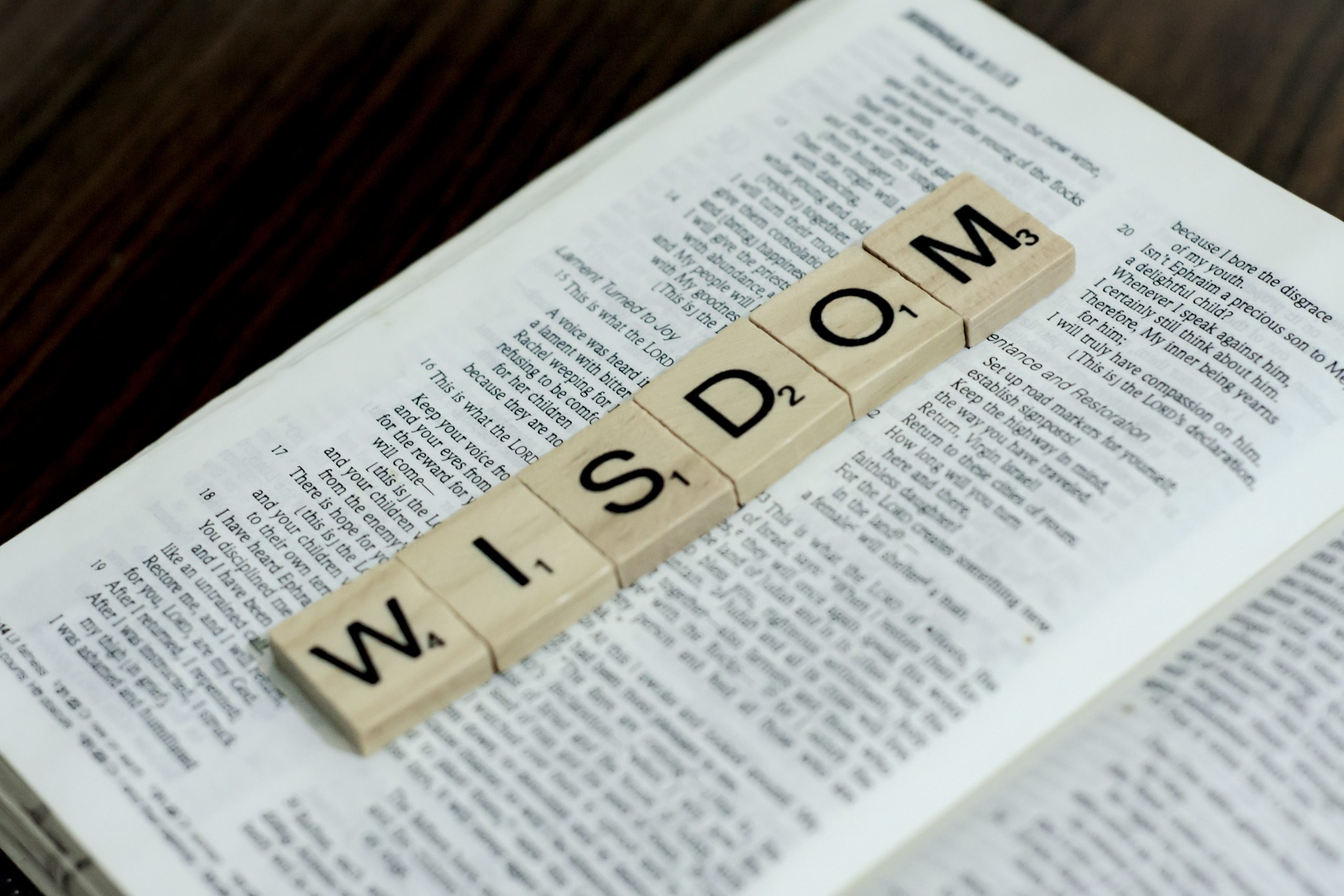 Scrabble letters spell wisdom on an open Bible