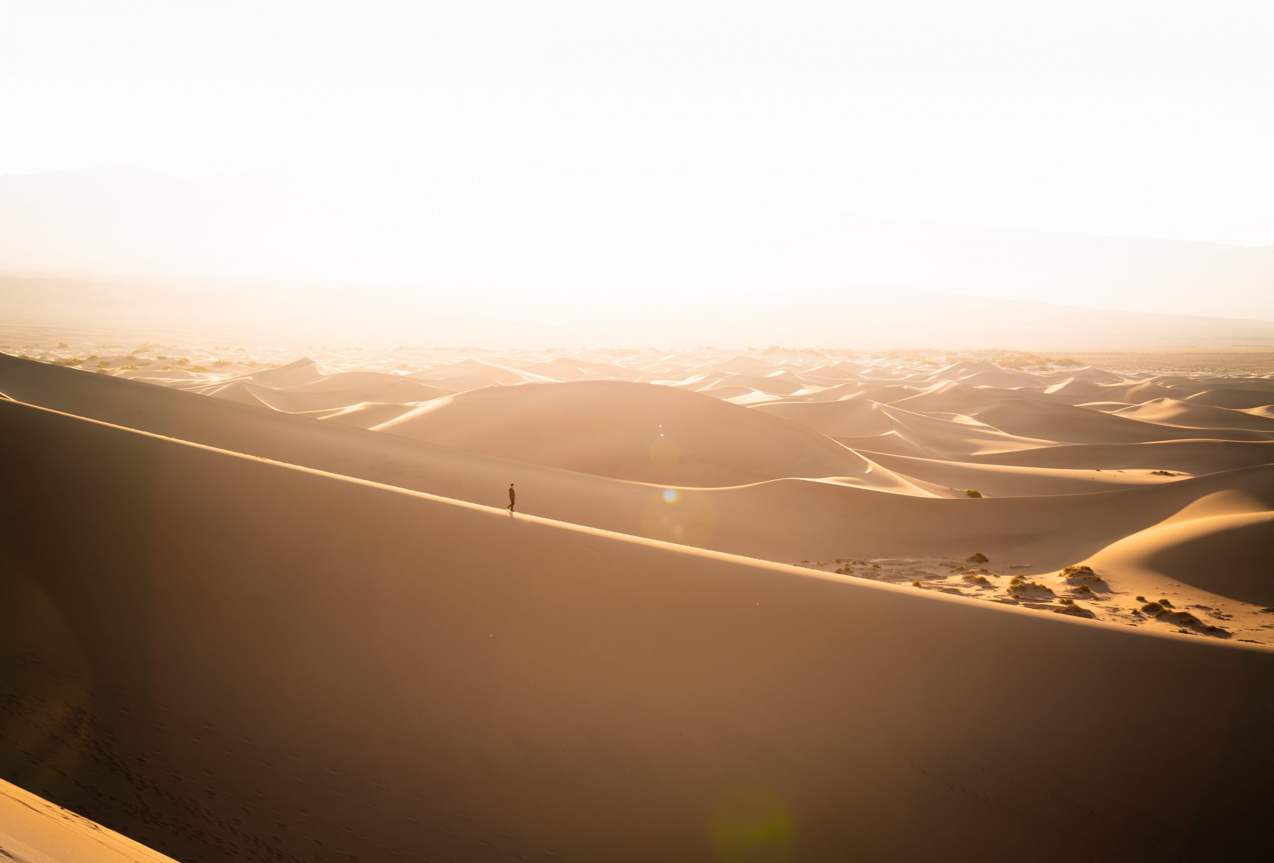 in the distance a man stands alone among desert hills