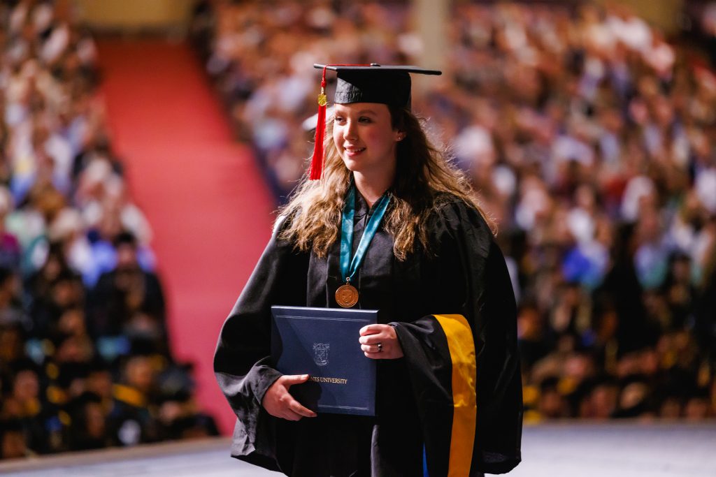 Woman from BJU School of Religion walks across stage with diploma