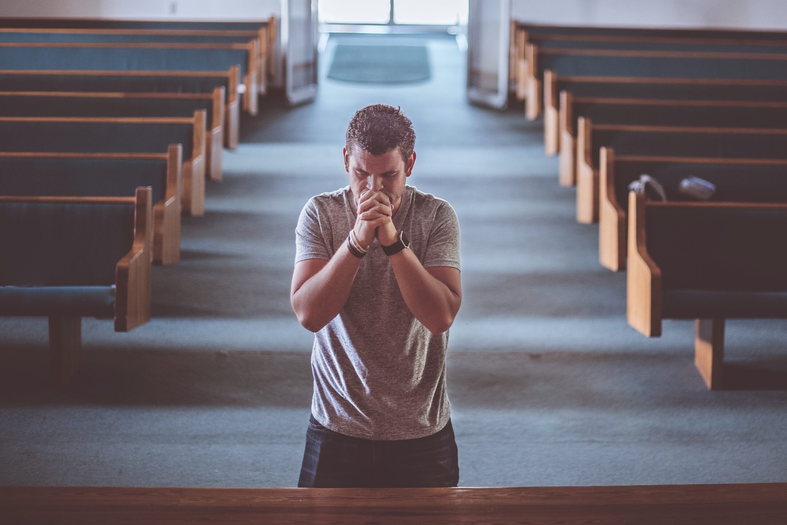 man prays, kneeling at front of church auditorium